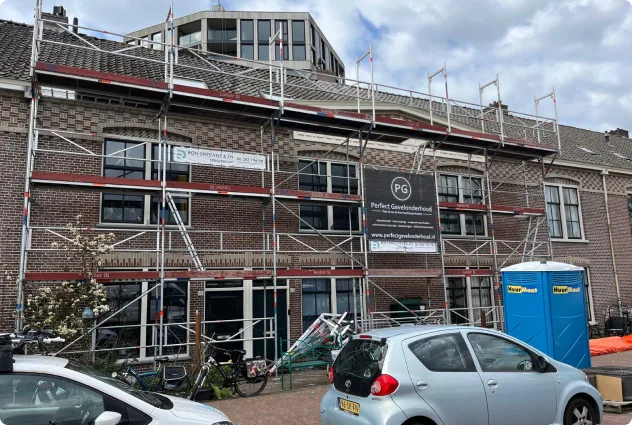 Steiger met reclamedoeken langs de gevel van een rij woningen